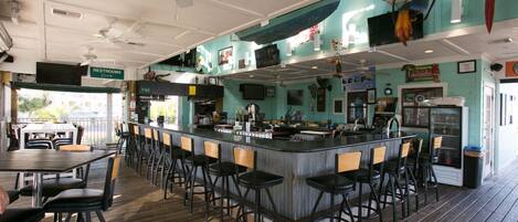 A bar area with a counter, stools, and ceiling fans.
