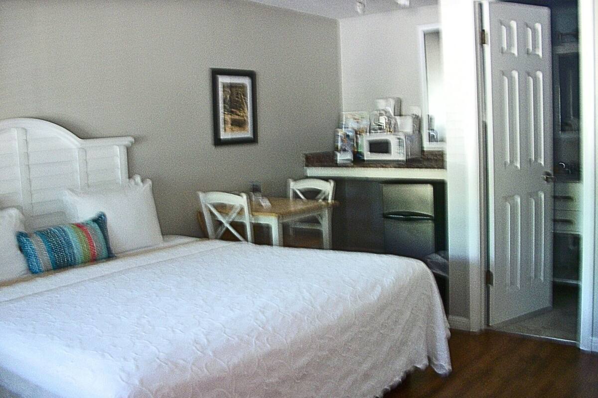 Un dormitorio con cama, escritorio, silla y microondas.