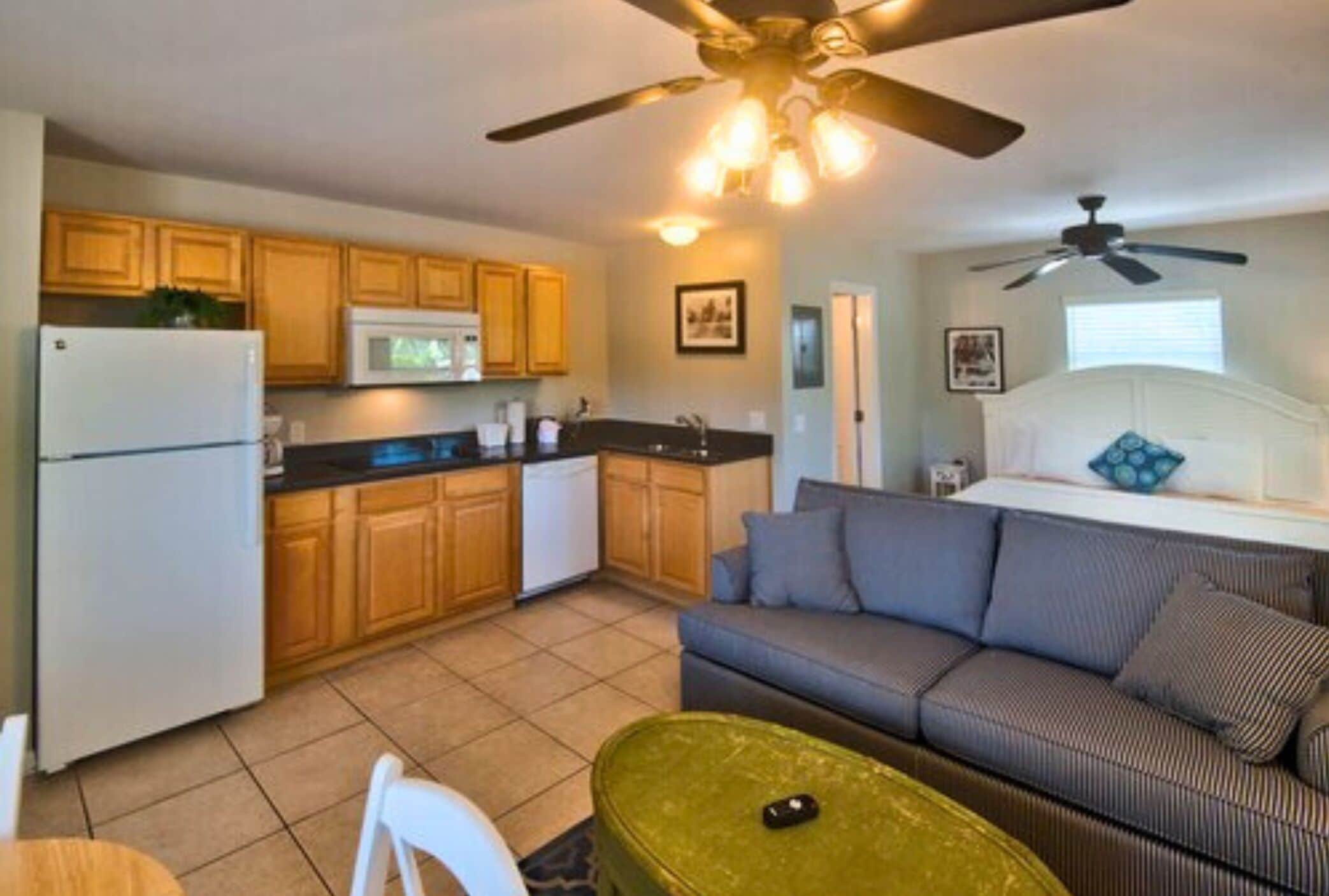 A compact living space with a kitchenette, a sofa, and a ceiling fan.