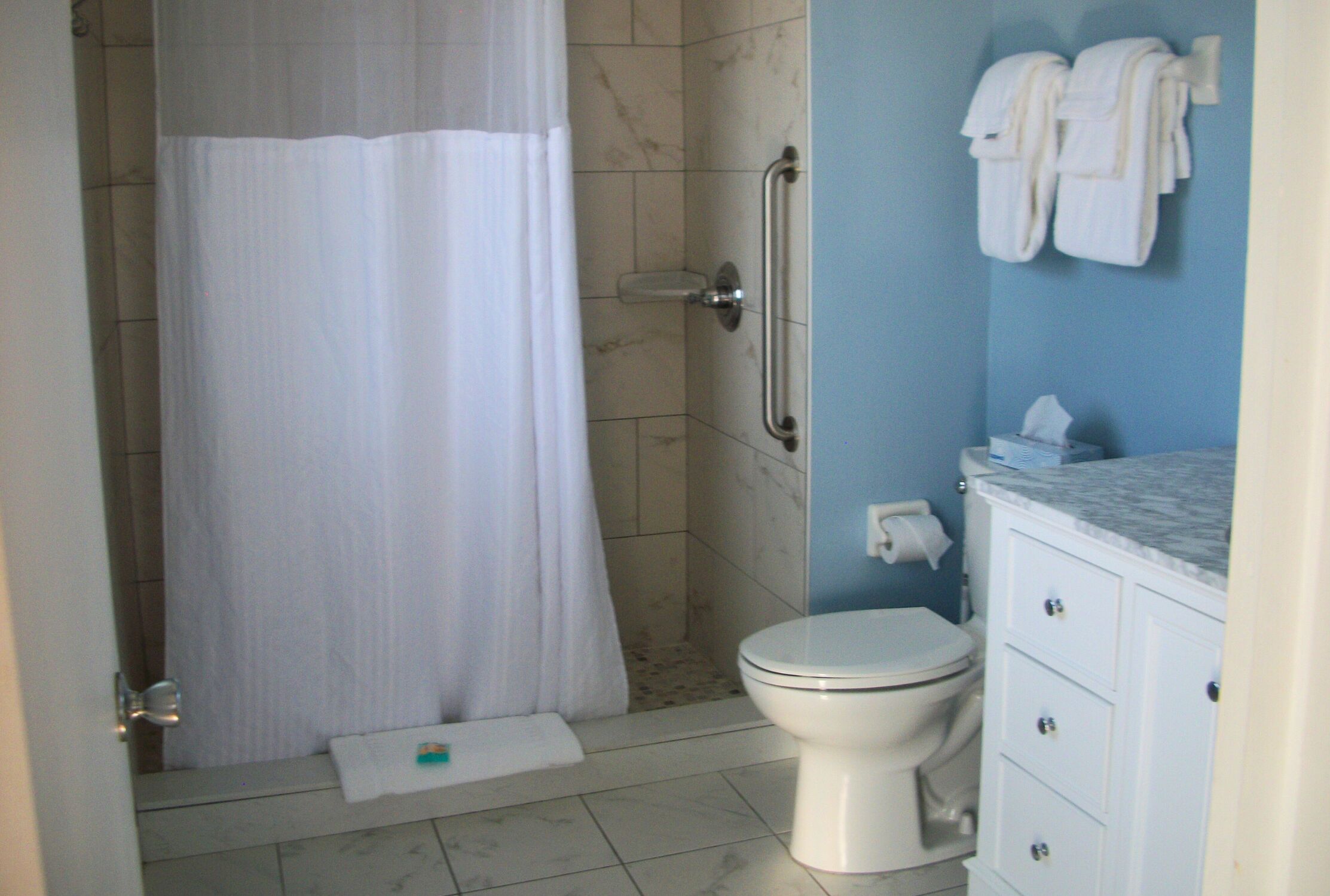 Een badkamer met douche, toilet en wastafel.
