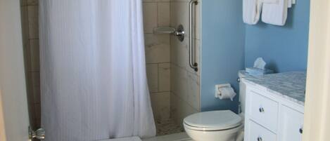 Een badkamer met douche, toilet en wastafel.