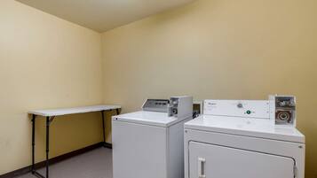 Une buanderie avec deux machines à laver blanches et une petite table.