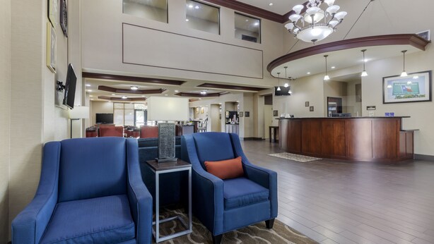 A spacious lobby with two blue armchairs, a reception desk, and a chandelier. - Comfort Suites Pflugerville - Austin North (Pflugerville)