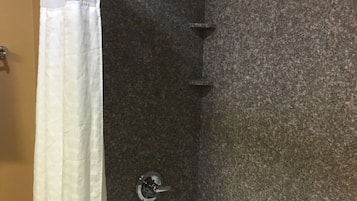 A bathroom with a bathtub, a shower curtain, and a granite wall.