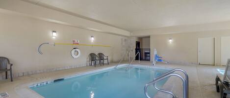 An indoor swimming pool with a clear waterline, a no diving sign, and a lifeguard chair.