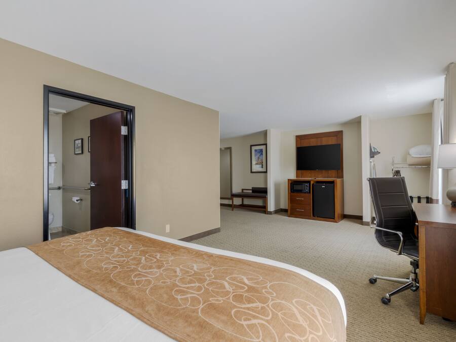 Una habitación de hotel con cama, escritorio, silla y televisión.