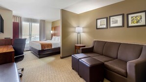 A hotel room with a bed, a sofa, a desk, a chair, a lamp, and framed pictures on the wall. - Comfort Suites Pflugerville - Austin North (Pflugerville)