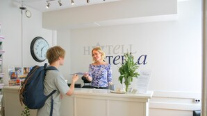 A reception desk with a clock and a sign reading "Hôtel Stella." - Hotell Stella (Uppsala)