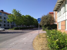 Calle con un letrero azul que indica un camino compartido para peatones y ciclistas.