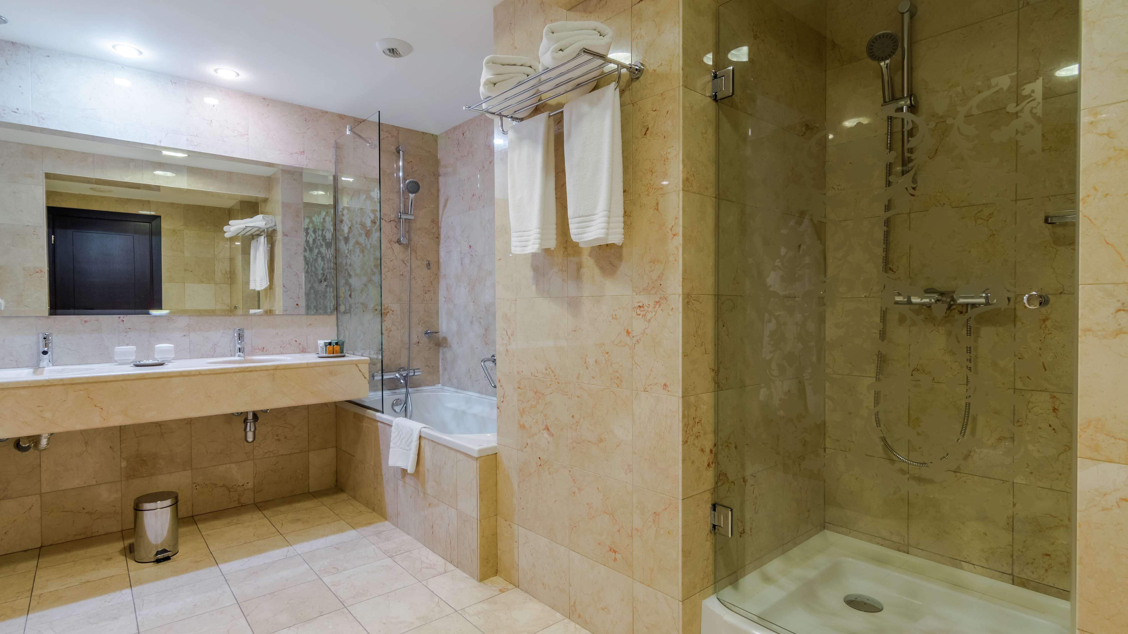 Un baño moderno con ducha de vidrio, bañera y tocador con espejo.