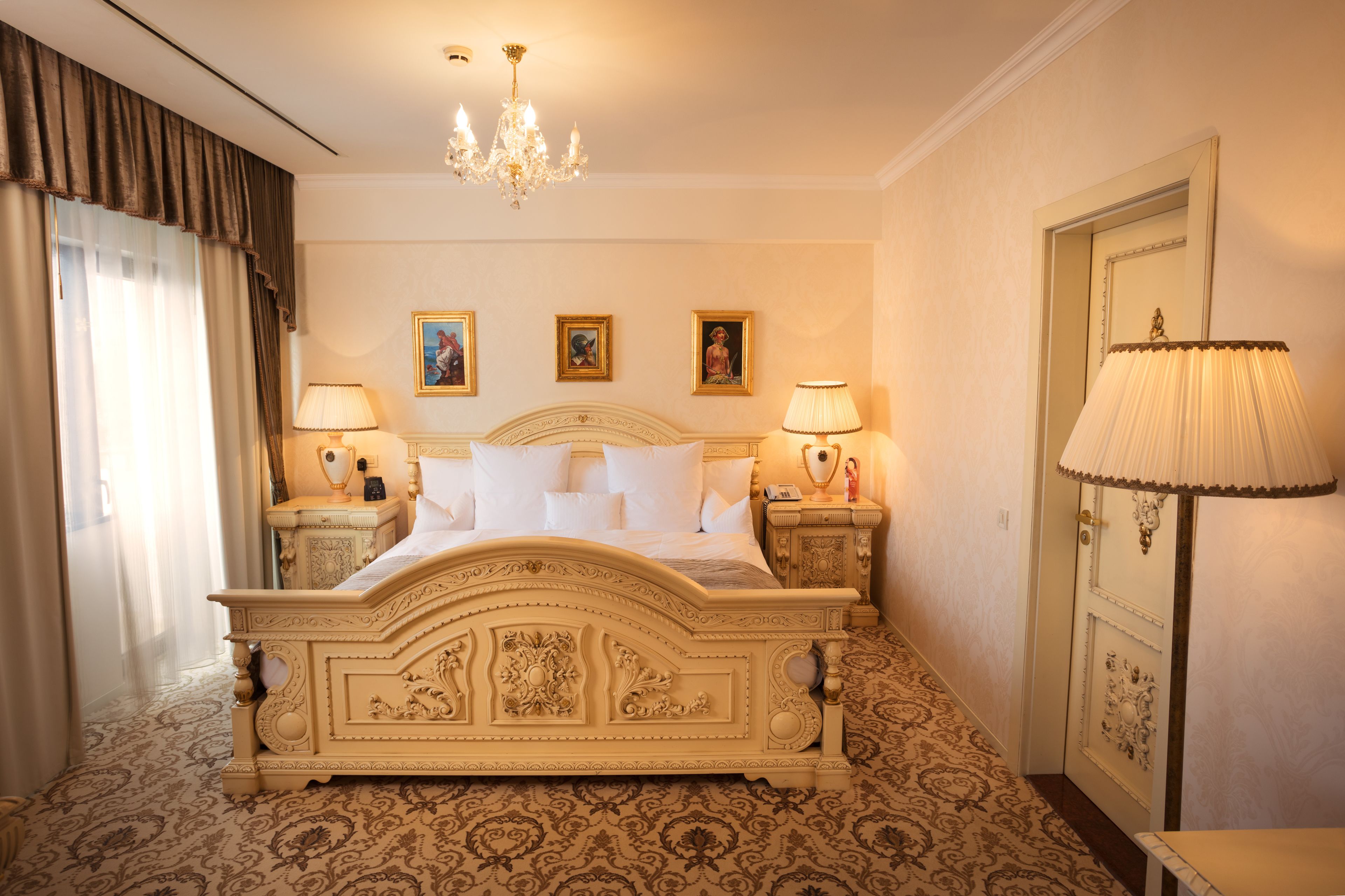 A large ornate bed with a headboard, two bedside tables, and a floor lamp.