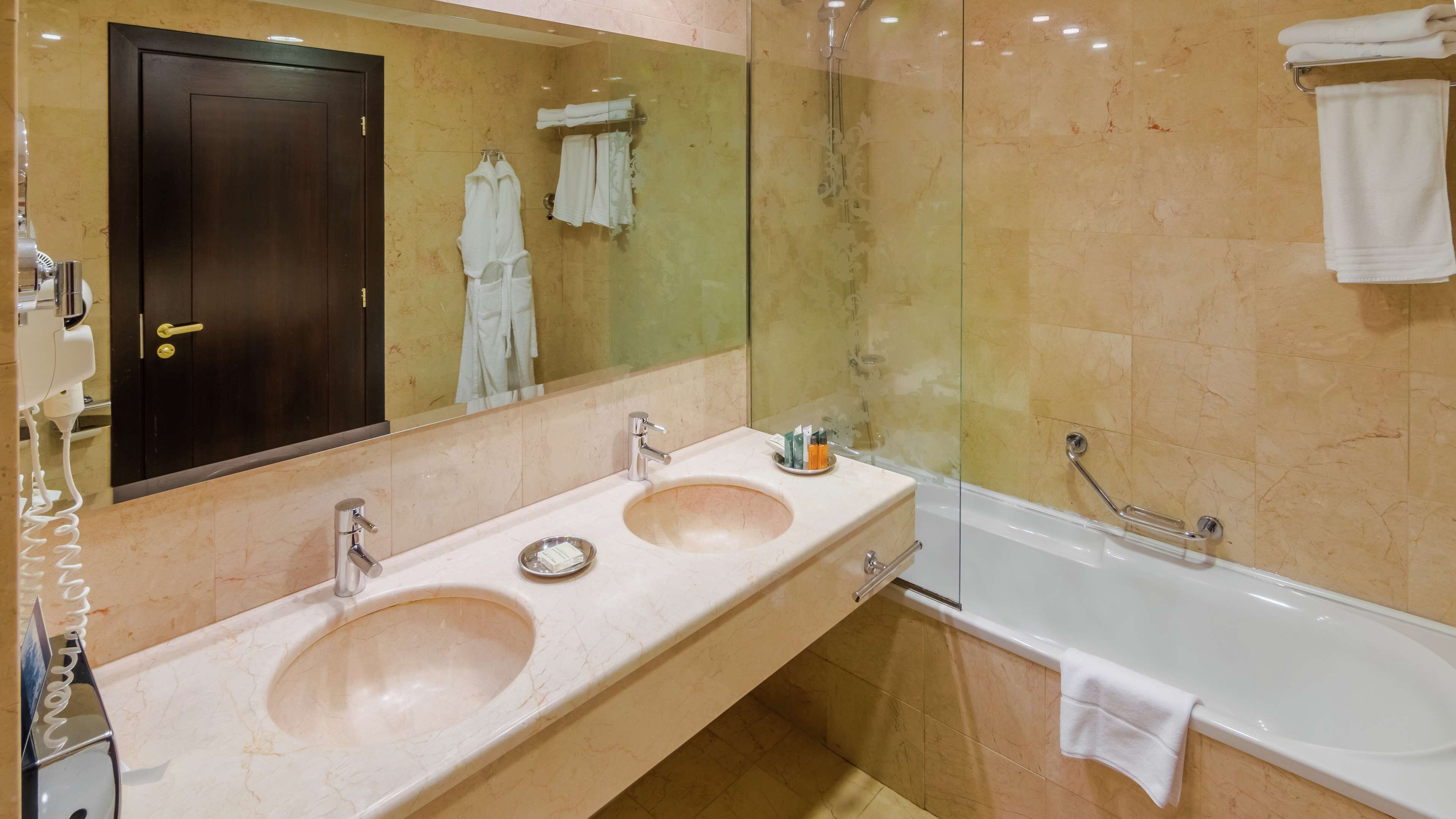 A bathroom with two sinks, a bathtub, and a glass-enclosed shower.
