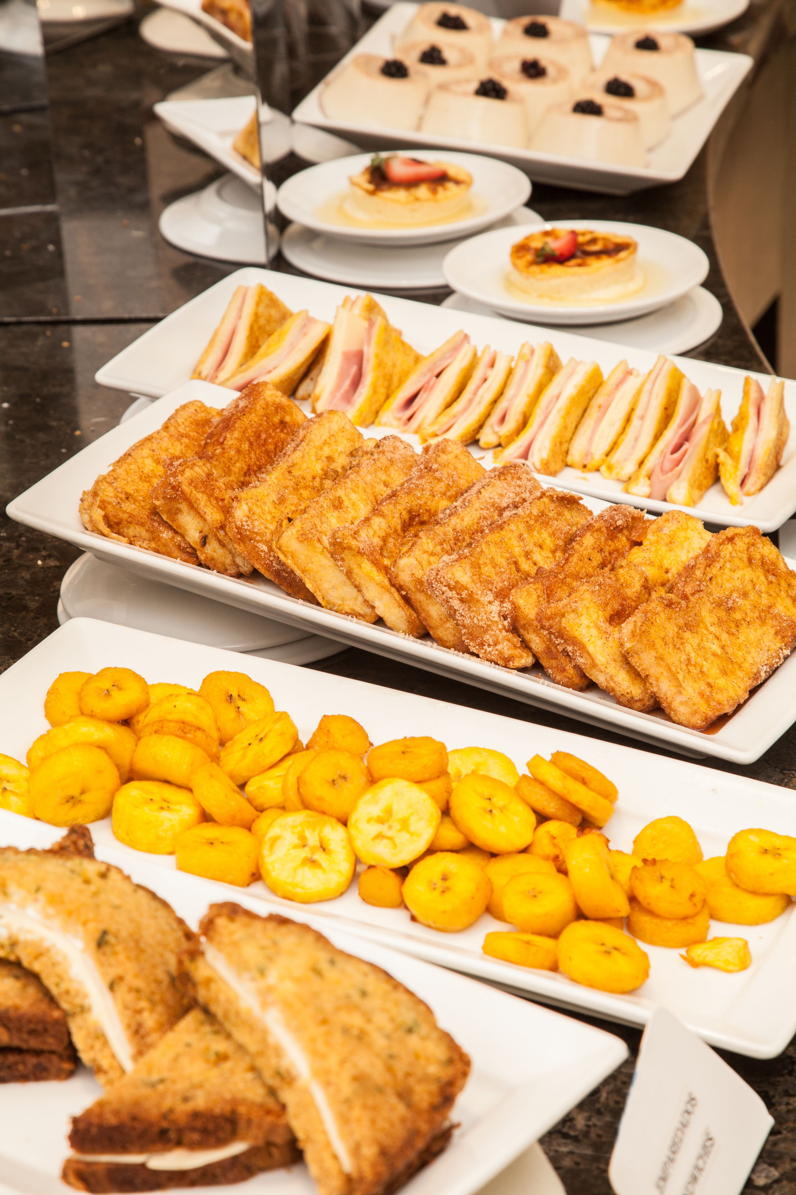 Un buffet proposant une variété de plats, notamment des sandwichs, des fruits et des desserts.
