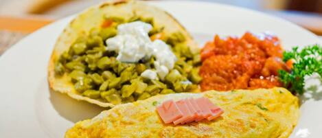 Un plato con una tortilla, un plato al horno con cobertura y una guarnición de salsa roja.