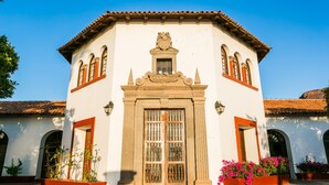 Un edificio de estilo colonial con una entrada central, ventanas de arco y un tejado de tejas.