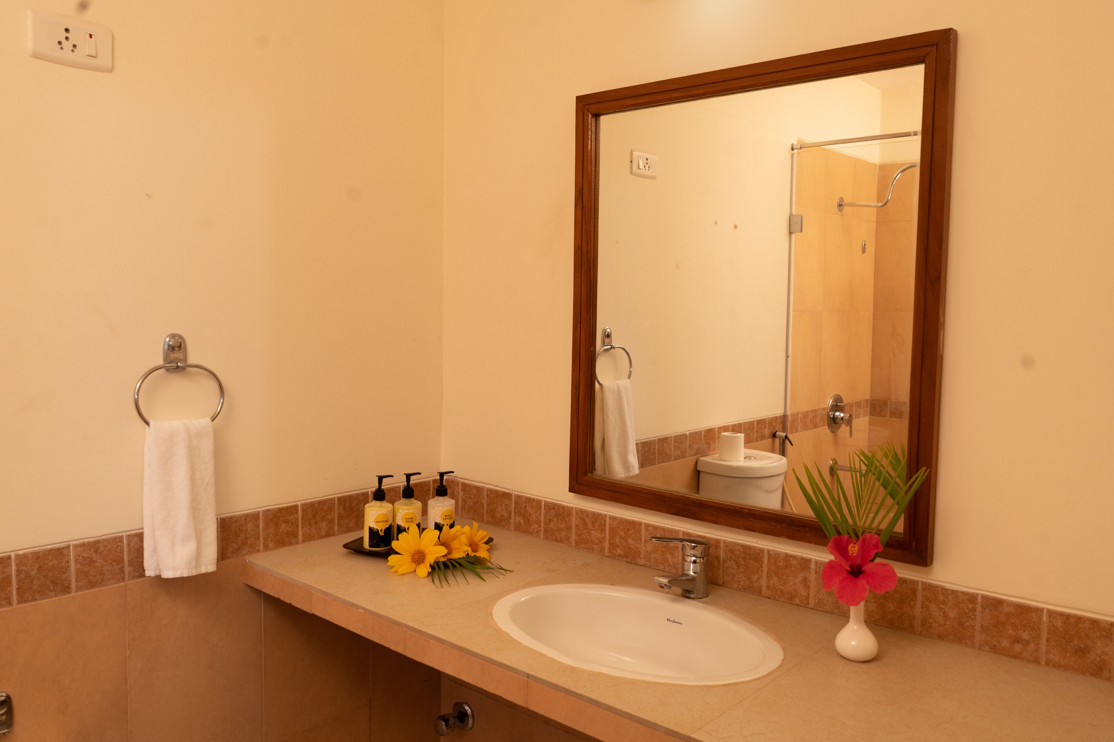 A bathroom with a sink, mirror, towel rack, and toiletries.