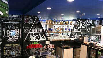 Interior de restaurante com cardápio em lousa, área de bar e diversos pontos de comida e bebida.