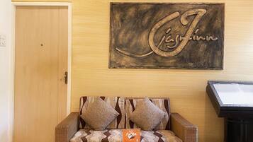A cozy room with a sofa, two wicker chairs, a ceiling fan, a wooden door, and a wall-mounted artwork.