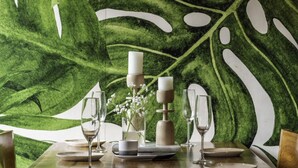 Una mesa de comedor dispuesta con platos, vasos y un centro de mesa con velas y flores.