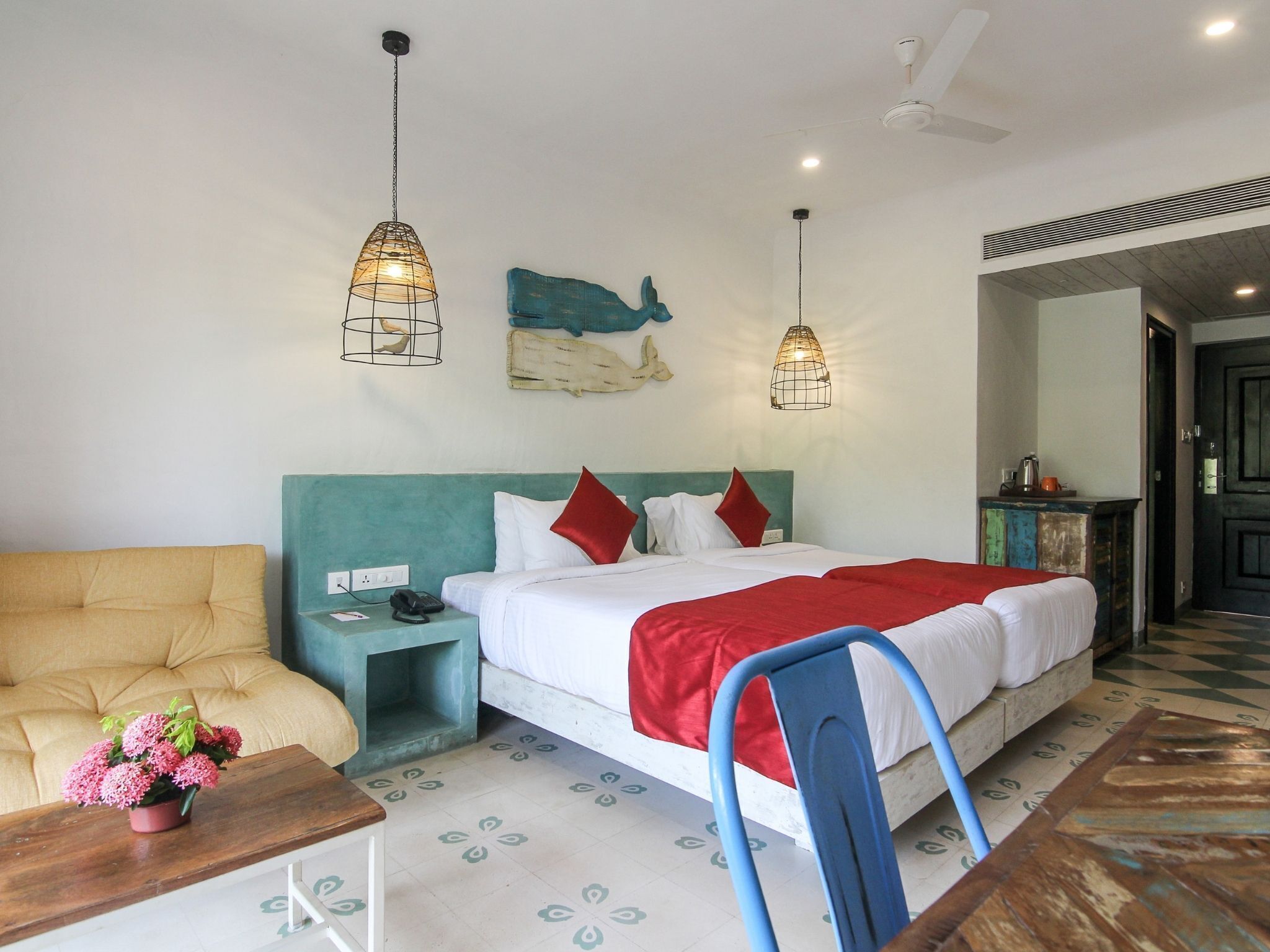 A bedroom with a bed, a nightstand, a chair, a table with a plant, and decorative wall art.