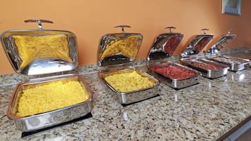 Un bufé con diversas opciones de comida en recipientes metálicos.