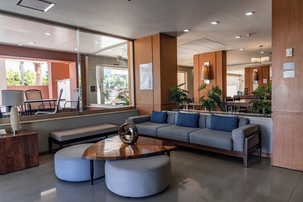 A modern lobby with a grey sofa, wooden coffee table, and a glass partition.