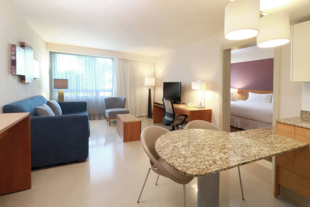 Una camera d'albergo con un letto, una scrivania, una televisione, un divano e un'area ristorazione.