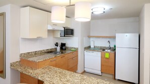 Una cocina compacta con encimeras de granito, microondas, lavavajillas y refrigerador.