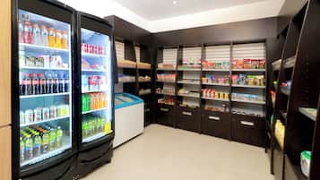 A self-service beverage area with refrigerated drink dispensers and shelves stocked with snacks and beverages.