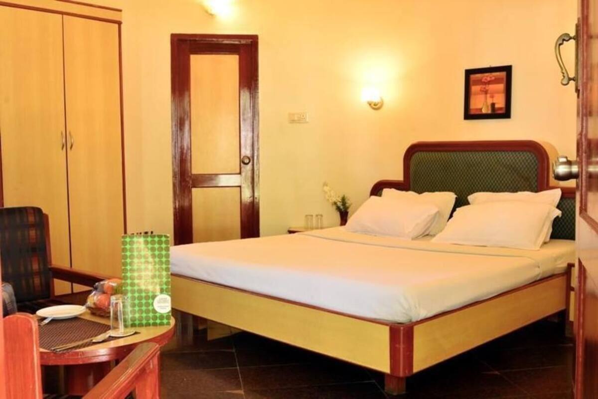 Une chambre d’hôtel avec un lit, une chaise, une table avec une assiette et un paquet vert, et une armoire.