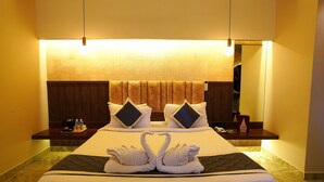 A hotel room with a large bed, two bedside tables, a headboard, and a mirror. - Green Coconut Resort (Tirupporur)