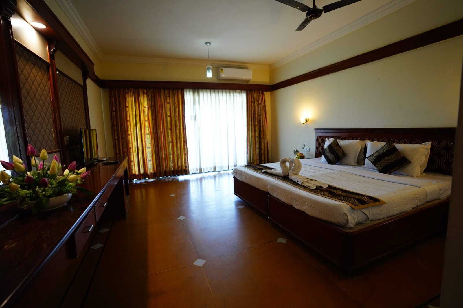 A hotel room with a large bed, a desk, and a view of the outdoors.