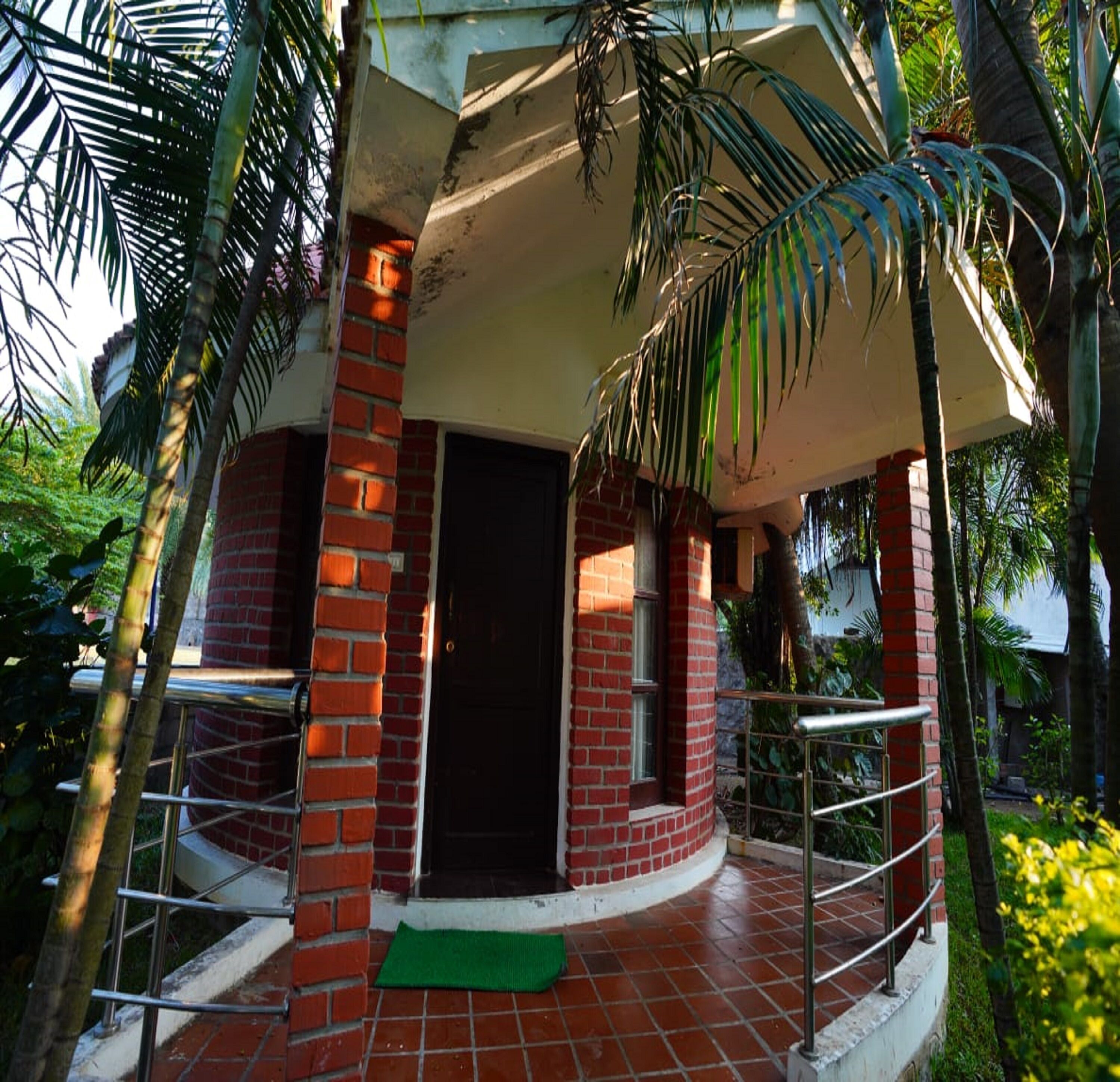 A brick building with a circular entrance, surrounded by palm trees and greenery.