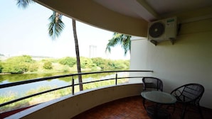 A balcony with a view of a river, two chairs, and an air conditioning unit. - Green Coconut Resort (Tirupporur)