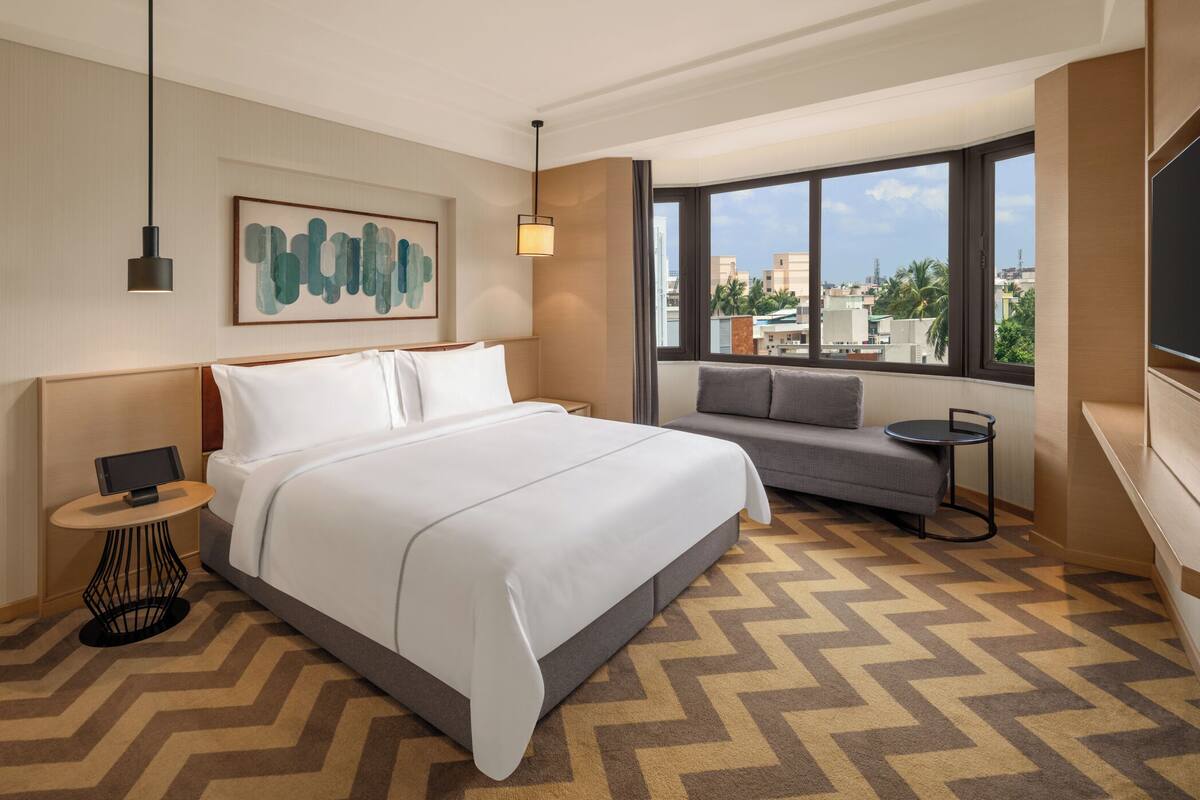 A hotel room with a large bed, a sofa, a small table, and a TV.