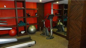 Un gimnasio con cinta de correr, bicicleta estática y diverso equipamiento de fitness.