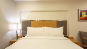 Una habitación de hotel con una cama, una mesita de noche, una lámpara y una silla.
