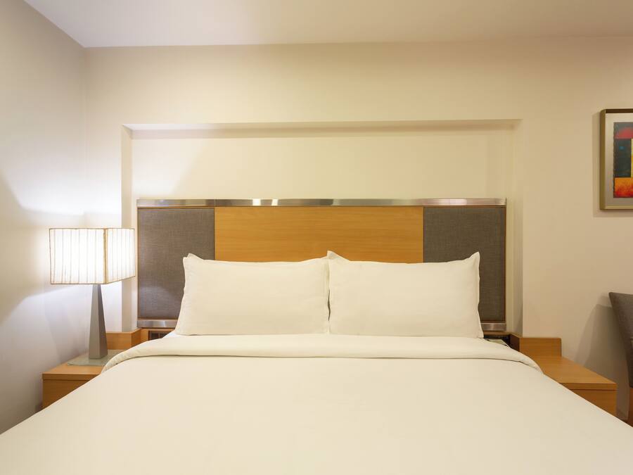 Una habitación de hotel con una cama, una mesita de noche, una lámpara y una silla.