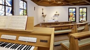 A church interior with wooden pews, a piano, and stained glass windows. - Europark Hotel International (Fuessen)