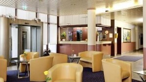 A hotel lobby with seating areas, a reception desk, and a clock on the wall. - Europark Hotel International (Fuessen)