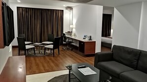 A modern hotel room with a dining area, a sofa, a desk with a computer, and a bed. - Hotel Abu Palace - Chennai (Chennai)