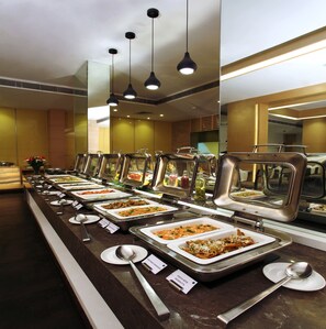 A buffet with multiple food stations, each with a serving spoon and a sign indicating the dish.