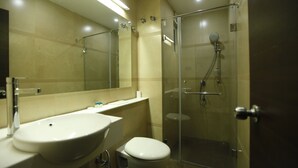Un baño moderno con ducha envuelta en vidrio, lavabo blanco y retrete.