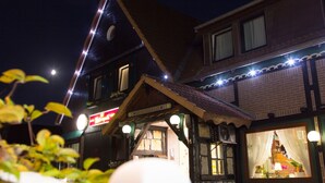 A traditional building with a sloped roof, a visible entrance, and string lights along the roofline. - Hotel Kaiserquelle (Salzgitter)