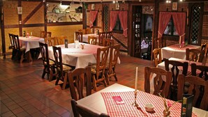 A restaurant with multiple tables and chairs, brick walls, and red and white checkered tablecloths. - Hotel Kaiserquelle (Salzgitter)