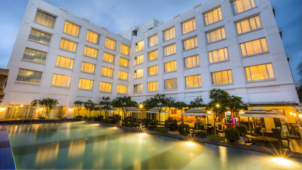 Un hotel de varios pisos con piscina y zona de estar al aire libre.