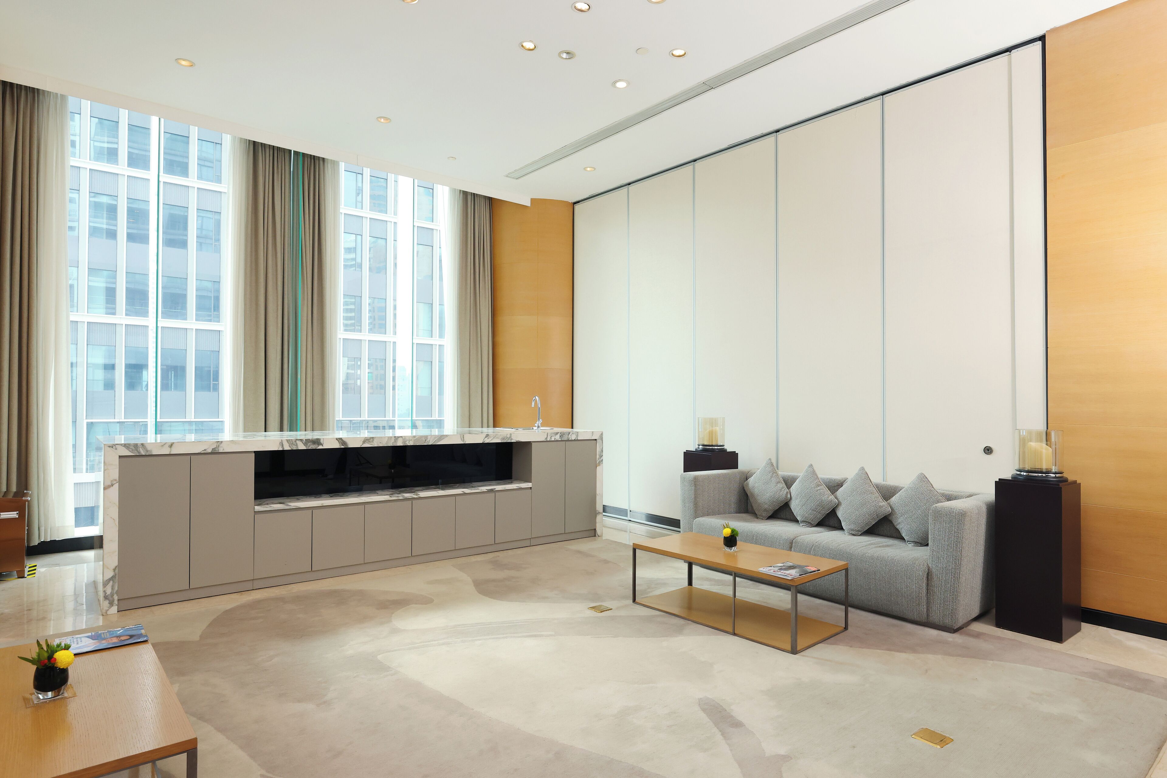 A modern living room with a sofa, coffee table, and a built-in kitchen area with a marble countertop.