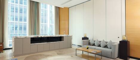A modern living room with a sofa, coffee table, and a built-in kitchen area with a marble countertop.