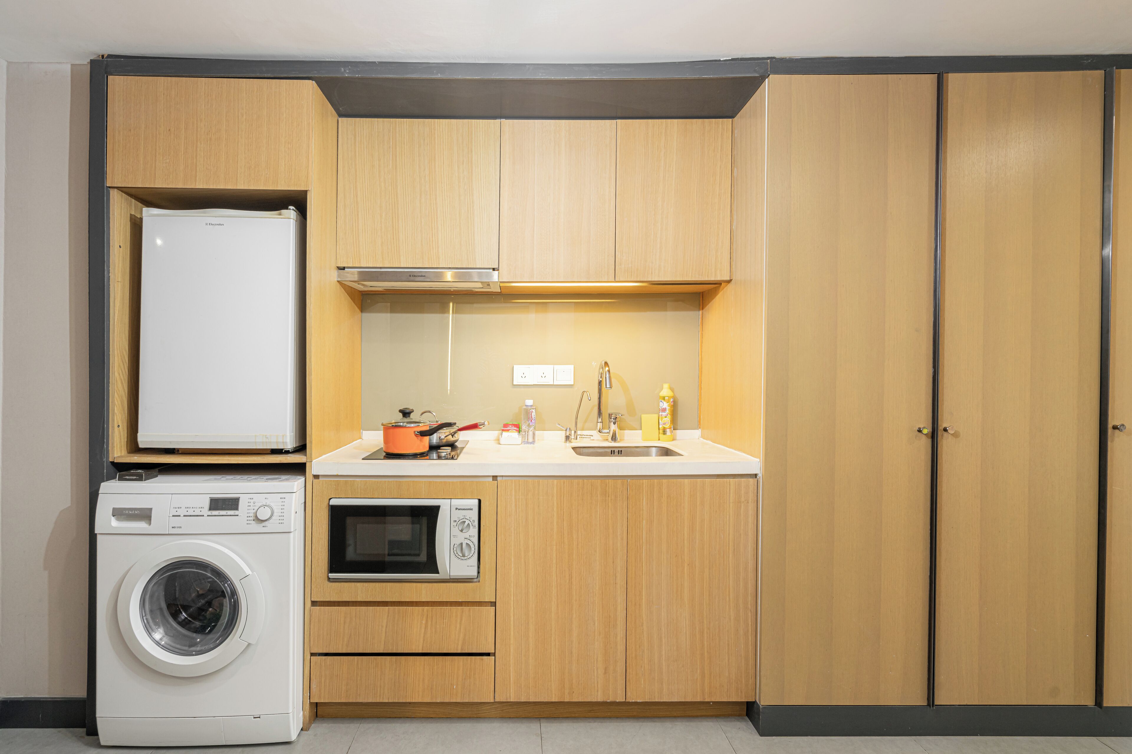 Uma cozinha compacta com máquina de lavar, micro-ondas e forno.