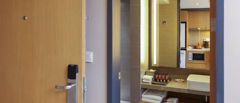 A modern bathroom with a wooden door, a mirror, a sink, and a towel rack.
